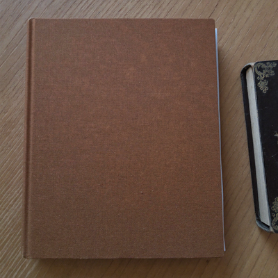 66-Page Bible Study Guide in brown, closed on a wooden table beside a Bible