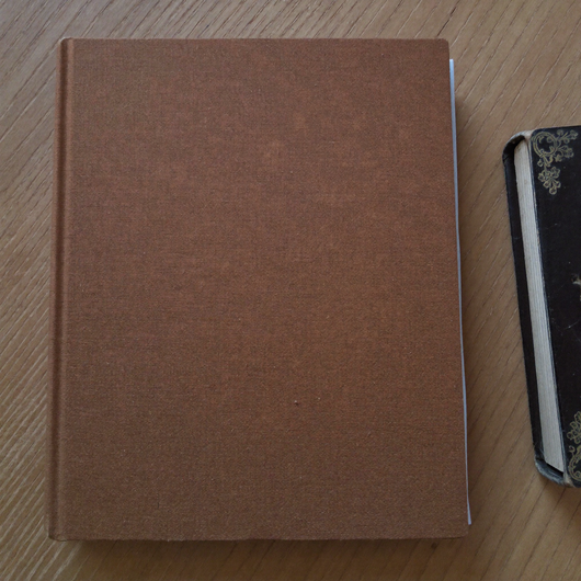 66-Page Bible Study Guide in brown, closed on a wooden table beside a Bible