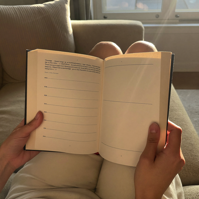 Woman holding the open study guide on her lap on a sofa