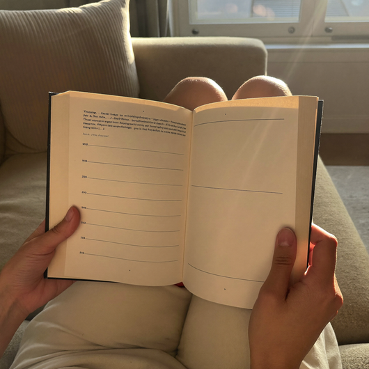 Woman holding the open study guide on her lap on a sofa