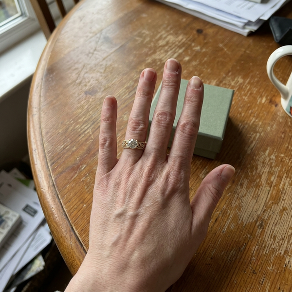 Maison Osonn Héritage Sculpted Ring on a hand resting on a wooden table