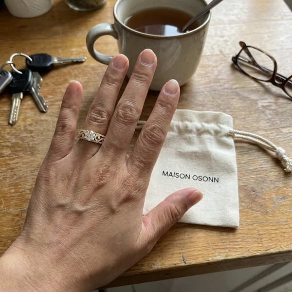 Maison Osonn Héritage Sculpted Ring on a hand beside its drawstring pouch